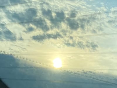 This media file shows a cloudy sky with the sun shining through, creating a bright halo effect. Two thin, dark wires run horizontally across the image, obscuring parts of the sky. The clouds appear puffy and varied in shade, with some areas illuminated by the sun and others casting shadows. The overall impression is of a bright, possibly late afternoon or early morning sky, given the soft light. There are no discernible people or objects apart from the wires. The location context of Нестюково, Russia, suggests a rural or semi-rural setting, though this is not explicitly visible in the image itself. The image evokes a sense of calm and perhaps a touch of melancholy due to the obscured sun and the presence of the wires. No text is visible.