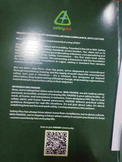 The image shows a page from a pamphlet with the title "Transforming Safety in Nigeria: Beyond Compliance, Into Culture" and a green logo with the name "safetyplus". The text discusses a vision for a safer future where safety is not just a requirement but a way of life. It refers to the founding of the organization in the UK in 1997 and its work to develop safety standards across borders. The text emphasizes the importance of going beyond safety compliance and creating a lasting attitudinal change. It introduces a program called PADDIE, described as a safety buddy that delivers practical safety guidance designed for real-life situations. The text encourages readers to scan a QR code to join the PADDIE community. The coordinates (latitude: 10.929, longitude: 11.476) indicate a location in Ashaka, Nigeria, but the image does not provide any information about this location or any specific scene.
