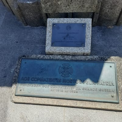 The image shows a monument with two plaques, likely in Vila Verde, Portugal, dedicated to soldiers of the First World War. The upper plaque, set in a granite base, commemorates the centenary of the Great War (1914-1918) and honors Portuguese combatants, dated 2014. The lower plaque, made of bronze, bears the inscription "AOS COMBATENTES MORTOS PELA PÁTRIA HOMENAGEM DOS COMBATENTES DA GRANDE GUERRA XI-1918 XI-1968" and features a crest with the inscription "LIGA DOS COMBATENTES". The monument is situated outdoors on a paved surface, with shadows suggesting it is daytime.