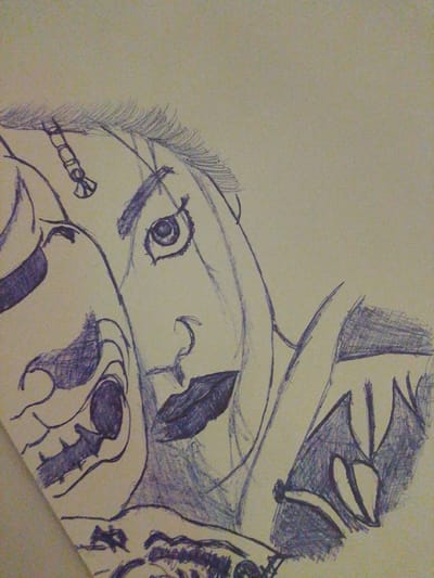 The image is a close-up, low-angle, hand-drawn sketch in shades of blue and purple on a light tan, textured background. The drawing depicts two faces in profile, overlapping and seemingly intertwined. The face on the left is skeletal with dark, hollow eye sockets, sharp teeth, and a protruding jaw. The face on the right is more human-like, with a prominent eye, a defined nose, and full lips. This face also has a unicorn-like horn on its forehead and what appear to be stylized wings or ornate headwear. The style of the drawing is rough and sketch-like, with visible lines and shading. The context of Rumuomasi, Nigeria is not discernible from the visual information provided in the image.