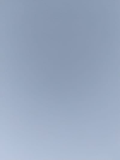 The image depicts a clear, pale blue sky, with subtle variations in tone. There are no discernible objects, people, or activities visible. The scene appears to be an outdoor environment, likely a sky view from a location within the city of Ak-Took, Kyrgyzstan. The light suggests it is daytime, with no clouds or atmospheric obstructions present. The overall impression is one of an empty, expansive sky.
