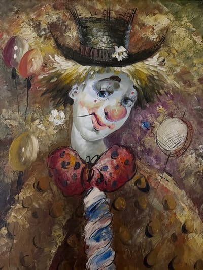The image is a painting of a clown's face lying on its side. The clown has pale skin, rosy cheeks, and large blue eyes with prominent eyelashes. The face is adorned with a small black top hat with a white flower, a large red polka-dotted bow tie, and a ruffled collar. A small white flower is painted beneath the face. Several colorful balloons are positioned near the bottom of the painting. The background is a mix of brown, beige, and purple hues, creating an abstract and somewhat melancholic atmosphere. The painting is not clearly indicative of any specific location in Levkovo, Russia. The style suggests oil on canvas.
