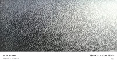 The image is a close-up, macro photograph of a textured, dark gray surface, possibly leather or a similar synthetic material, exhibiting a repeating pattern of small, raised bumps or dimples. The lighting creates subtle highlights and shadows that accentuate the texture. The bottom of the image contains overlaid text: "NOTE 40 Pro 2026.06.19 03:02 PM 23mm f/1.7 1/200s ISO88 null." There are no people or discernible environmental elements of Buzovna, Azerbaijan in this image.