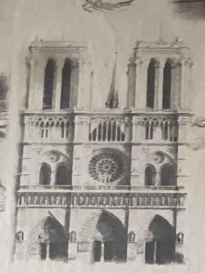 The image depicts a detailed pencil drawing of the facade of Notre Dame Cathedral in Paris, France. The drawing captures the architectural features, including the rose window, the towers, arched doorways, and intricate detailing. The drawing has a tonal quality with variations in shading and texture, suggesting a meticulous rendering of the building's structure. The image is monochromatic, contributing to a sense of timelessness and highlighting the architectural design. The image does not depict Krasnoyarsk, Russia.