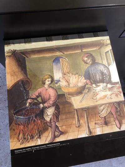 This image shows a medieval illustration of poultry preparation. Two men are depicted. One man, standing at a table, is holding a plucked chicken. Another man is standing beside a large pot, which appears to contain boiling water. The men are inside a room with a tiled floor and paneled walls. The text on the side of the image provides the title "Préparation des volailles / Preparation of poultry / Geflügelzubereitung" and indicates the source of the illustration as "Tacuinum Sanitatis, milieu XV siècle, Paris, Bibliothèque nationale de France, Latin 9333, f. 78r," suggesting it is a French manuscript from the 15th century in Paris. There is no information to suggest it has anything to do with Veytaux, Switzerland.
