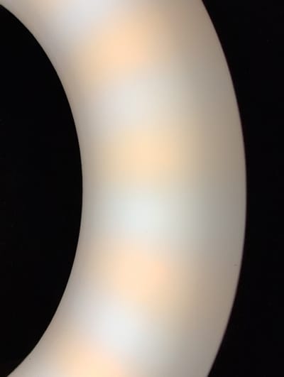 The image shows a close-up, abstract view of a curved, translucent object against a black background. The object appears to be illuminated from within or behind, with soft, warm light creating a gradient of color from white to a peachy orange. The texture of the object is smooth and matte. The image does not contain any discernable elements that would allow for identification of a specific location in Louisville, United States of America.
