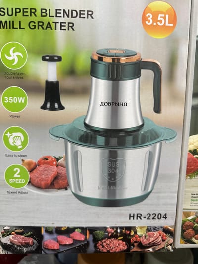 The image displays the packaging of a kitchen appliance, a "SUPER BLENDER MILL GRATER." The packaging features a prominent illustration of the appliance itself, which is a silver and green multi-functional food processor with a stainless steel bowl and a clear plastic lid. Text on the packaging highlights its features, including "350W Power," "Double layer four knives," "Easy to clean," and "2 SPEED Speed Adjust." A prominent "3.5L" is also displayed, indicating its capacity. Below the appliance, there are images of raw meat, suggesting its intended use for mincing or grinding. The model number "HR-2204" is visible at the bottom. The background is a light, neutral color. There is no indication of the location being Kara-Suu, Kyrgyzstan, or any people present in the image.
