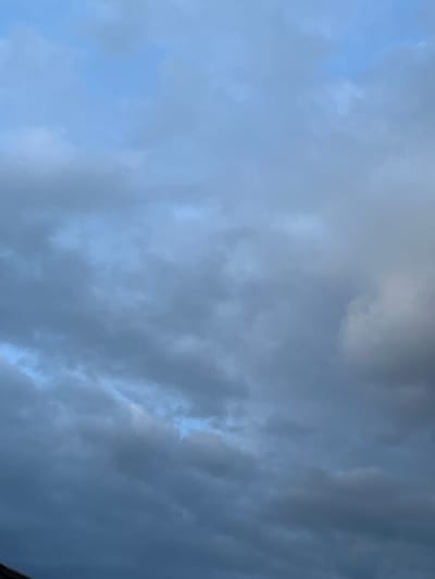 The image shows a cloudy sky above Stoke-on-Trent, United Kingdom. The clouds are dark and grey, with some patches of blue sky visible through them. The lighting suggests it is either early morning or late evening. There are no people or objects clearly visible in the frame, only the sky. The lower part of the image shows a dark, indistinct edge of what could be a building or trees.