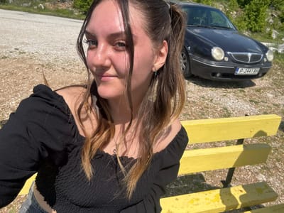 A young woman lies on a yellow wooden bench outdoors, with a black car parked nearby. The license plate of the car is P-2441AH. The location is Lipnitsa, Bulgaria, as suggested by the license plate.