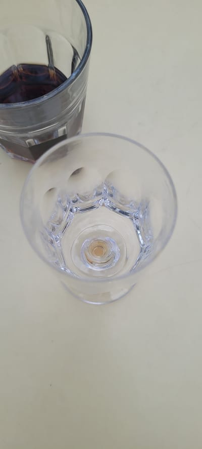 An overhead shot shows two glasses on a neutral-colored surface. The glass in the foreground is empty and clear with a hexagonal pattern at the bottom. The glass in the background is partially visible and contains a dark red liquid. There is no indication of a specific location in Dietzenbach, Germany, nor are there any people or actions depicted.
