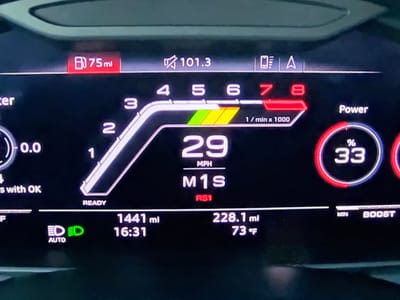 The image shows a close-up of a car's digital dashboard display. The dashboard indicates a fuel range of 75 miles and a speed of 29 mph. There is also a tachometer showing engine RPMs up to 8, with the needle indicating around 4.5. Other displayed information includes the time, odometer reading (1441 miles), trip distance (228.1 miles), and an outside temperature of 73°F. A "Power" gauge shows 33%. An icon for automatic headlights is illuminated green, indicating they are active. The location is specified as Bezden, Bulgaria, but this information is not visually verifiable from the image itself.