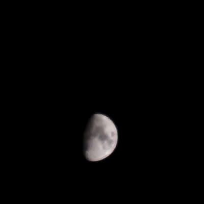 The image shows a close-up view of the Moon against a black sky. The Moon is partially illuminated, with the right side being brighter and the left side in shadow. The surface of the Moon shows visible craters and variations in texture. The image is entirely dark except for the Moon, suggesting it was taken at night. There are no elements of a cityscape or any indication of the specific location in Illescas, Spain.