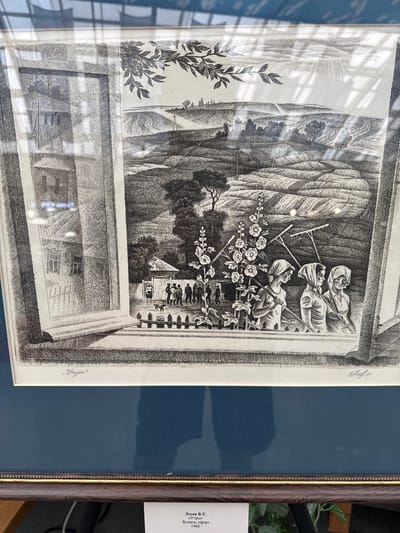 This is a black and white etching depicting a pastoral scene, likely rural, with elements of human activity and nature. The top portion of the etching shows three figures, two women and one man, dressed in simple, draped clothing and head coverings. They appear to be resting or engaged in light labor, each holding a rake. In front of them, a profusion of flowers, possibly roses, is rendered with delicate detail. Behind them, a steep, textured hillside rises, with sparse trees suggesting a rugged landscape. The lower portion of the etching presents a more constructed scene, featuring architectural elements that resemble buildings or structures viewed through a framed opening, perhaps a window or an archway. This interior view shows patterned walls or textures and hints at rooms or courtyards. The overall atmosphere is serene and perhaps idyllic, with the sun's rays suggested by hatched lines in the upper left. The etching is signed in the lower right with what appears to be "Утро" (Utro), meaning "Morning" in Russian. A label on the right side of the frame contains Russian text, identifying the work as "Лосев В.Т. «Утро» бумага, офорт 1980." This translates to "Losev V.T. 'Morning' paper, etching 1980." The location context is the settlement of the 1st division of the Maslovsky state farm, Russia.