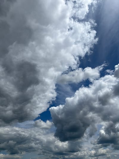 The image depicts a dynamic sky filled with a mixture of dark, heavy storm clouds and brighter, fluffy white clouds against a deep blue sky. The clouds are varied in texture and density, with some appearing wispy and others thick and voluminous. The overall impression is one of an approaching storm or a sky clearing after one. There are no people, subjects, or objects visible in the image other than the clouds and the sky. The scene is devoid of any specific urban or geographical markers that would place it in Ol'gokhta, Russia.
