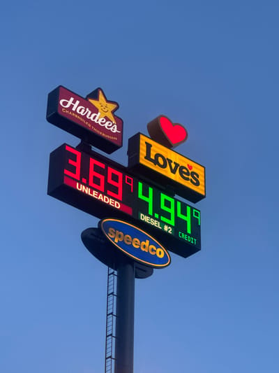 A tall sign displays prices for unleaded gasoline and diesel fuel. The sign features the Hardee's and Love's brands, and the Speedco logo is visible at the bottom. The sky is a clear, pale blue, suggesting it is either early morning or late evening. The gas prices displayed are $3.69 for unleaded and $4.94 for Diesel #2.