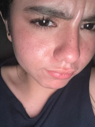 A close-up portrait of a woman's face. Her eyes are open, and she appears to be wearing mascara. Her lips are slightly parted. The background is a dark blue fabric. It is not possible to determine the location in College Station, United States of America from this image.