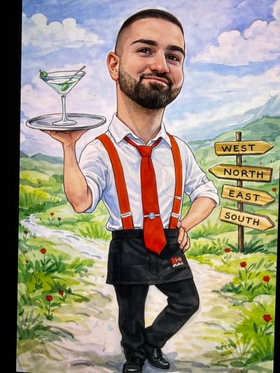 This is a full-body caricature painting of a light-skinned male with short dark hair, a beard, and a mustache, depicted in a standing pose with a slight smile. He wears a white collared shirt with rolled-up sleeves, red suspenders, a red necktie with a silver tie clip, a black half-apron displaying a red logo (partially visible, resembling "M+G Plus"), black trousers, and black shoes. In his raised left hand, he balances a silver serving tray holding a martini glass containing a green beverage and two green olives on a toothpick. His right hand is placed on his hip. The background shows a winding light-colored path through green grass punctuated by small red flowers, leading to green hills under a blue sky with white clouds. To the right of the figure, a wooden signpost features four directional arrows, labeled from top to bottom: "WEST", "NORTH", "EAST", and "SOUTH". The scene is a stylized, scenic outdoor environment, notionally located within or associated with the city of Γεωπονικά, Greece.