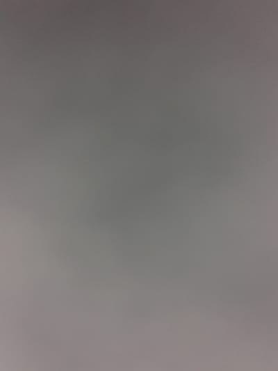 The image is a plain, gray, textured background with a subtle gradient, darker at the top and lighter towards the bottom. No objects, people, or environment details are visible. The image is a uniform color and texture.