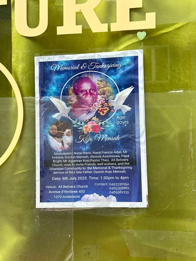 The image is a memorial announcement for Kojo Mensah, located on a glass door. The announcement is printed on a white sheet of paper adhered to the glass door. It is partially visible with a bright green background. The top of the glass door reads "URE" in large yellow letters. There is a pink heart sticker to the right of the word "URE". The memorial announcement is framed in a white border and features a picture of the deceased in a white oval with a blue background. The announcement lists the following details: The deceased is Kojo Mensah. His age is 90 years. The announcement was posted by Abusuapaanin Nana Manu, Nana Francis Adjei, Mr. Antoine, Gordon Mensah, Akosua Asantewaa, Papa Bright, Mr. Agyeman Kusi, Pastor Theo. The announcement invites all believers to the memorial and thanksgiving service for the late Father. The service is taking place on July 6th, 2025, at 1:30pm to 4pm, at All Believers Church, Avenue d'Itterbeek 432, 1070 Anderlecht, in the city of Saint-Josse-ten-Noode, Belgium. The announcement also provides two phone numbers for the service.