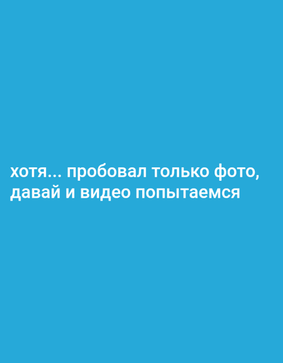 The image is a close-up of a bright blue background with white text. The text is in Russian and reads: "хотя... пробовал только фото, давай и видео попытаемся". This translates to "although... I only tried photos, let's try video too." The text appears to be a caption or a message related to media creation. There are no people, objects, or discernible scene details visible in the image, other than the text itself. The setting is a plain, solid blue color, offering no clues about the time of day, weather, or location. The overall impression is simple and direct, focusing entirely on the written message.