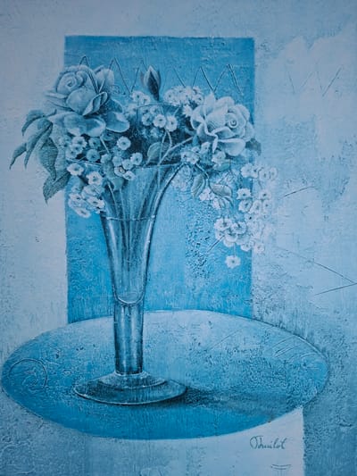 The image is a painting in shades of blue, depicting a still life arrangement. A tall, clear glass vase filled with a bouquet of roses and smaller white flowers stands on a round, oval-shaped surface. Behind the vase, a textured blue rectangular panel is visible. The background of the painting is also textured and predominantly white with blue undertones, featuring abstract zigzag patterns. The signature "Thuilot" is visible in cursive script in the lower right corner of the painting. There are no people, actions, or interactions depicted in this artwork. The painting does not contain any elements or context that would allow for its location to be identified in the city of Greifswald, Germany.