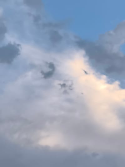 The image shows a cloudy sky above the city of Dillingen an der Donau, Germany. The clouds are a mix of gray and white, with some patches of blue sky visible. The lighting suggests it is either early morning or late afternoon, as there is a warm glow on some of the clouds. There are no people or specific objects visible in the frame, just the natural environment of the sky.