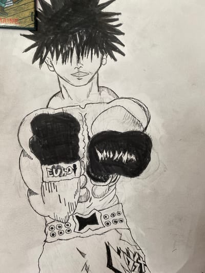 This is a sketch of a person wearing boxing gloves and boxing shorts, drawn in a manga style. The person has spiky black hair that obscures their eyes. They are wearing a top that resembles a tank top or a workout shirt, and their boxing shorts have a decorative belt with circular studs. The left boxing glove has the letters "EURO" written on it. The sketch is done in black ink and pencil on a piece of paper. There is a small, rectangular object in the top left corner of the image, which appears to be a magnet with text that includes "MAINE". The drawing does not depict any specific location within the city of Elizabeth City, United States.