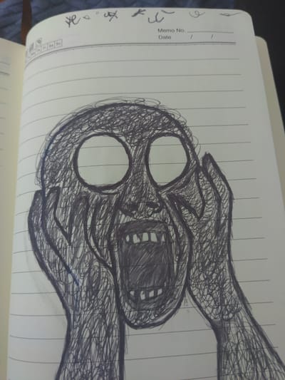 The media file is a close-up, overhead shot of a page in a lined notebook. The notebook is open, revealing the left and right pages. The background appears to be a blurry, dark surface, possibly a table or fabric.
The primary subject is a dark, sketchy drawing that dominates the right page of the notebook, extending slightly onto the left. The drawing depicts a distorted, screaming face with large, empty eye sockets and an open mouth revealing teeth and a tongue. Over the face, two hands are drawn in a scribbled, rough style, appearing to be either pressing down on or holding the head. The overall impression of the drawing is one of anguish or terror.
On the left page, near the binding of the notebook, there are some faint handwritten marks or doodles in black ink. Above the drawing, the notebook has pre-printed lines for "Memo No." and "Date," with a single dash on each line. At the bottom of the left page, there are small boxes with letters like "Mo," "Tu," "We," "Th," "Fr," "Sa," and "Su," suggesting a calendar format.
The lighting suggests it is daytime, likely indoors due to the controlled lighting and the presence of a notebook. There are no specific weather or location cues other than the notebook itself, which is a common object. The emotion conveyed by the drawing is distress or extreme fear. There is no discernible narrative or event taking place beyond the creation of the artwork.