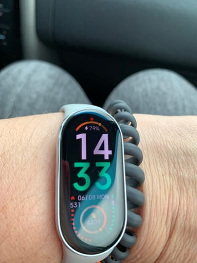 The image shows a close-up of a person's wrist wearing a smart band. The smart band displays the time as 14:33, the date as 06/08, and the day as Monday. It also shows a battery level of 79%, a step count of 531, and a distance of 4409. The smart band is attached to a coiled gray strap. The person's wrist is covered in hair, and the background consists of gray fabric, likely clothing. There is no indication of the location being in Сваткаўскі сельскі Савет, Belarus.