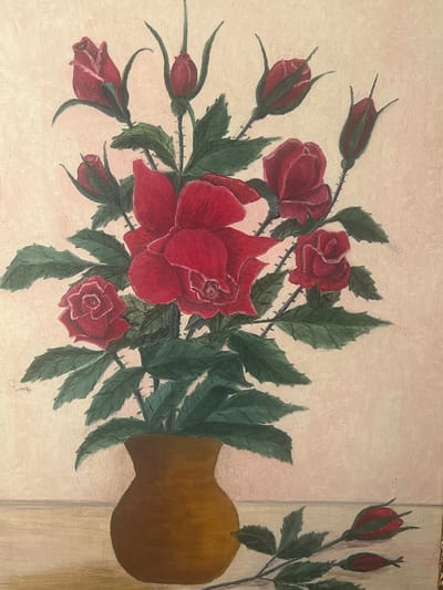 An oil painting depicts a bouquet of red roses in a vase, placed on a wooden surface against a light pink background. The roses are rendered in various stages of bloom, with some fully opened and others as buds. Dark green leaves and thorny stems are visible, adding texture and detail to the floral arrangement. A single rose stem with two buds lies across the foreground, extending from the right side of the image. The vase is a simple, brown, earthenware pot with a rounded base and a narrow neck. The painting is in a realistic style, with visible brushstrokes that give it a textured appearance. The lighting appears soft and diffused, casting no harsh shadows. There are no people or animals present in the painting, and the setting is a still life composition. This painting is not located in the city of Ringsted, Denmark, or any specific city. It is a studio artwork and does not depict a real-world location.