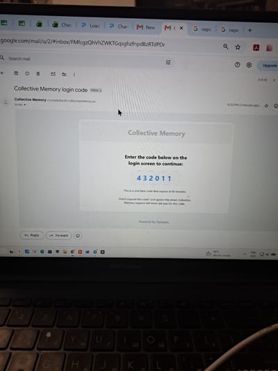The image shows a laptop screen displaying an email from "Collective Memory" with a login code. The email contains the code "432011" and a message stating it's a one-time code that expires in 10 minutes. The laptop is open, and a portion of the keyboard is visible at the bottom of the image. The background is dark, suggesting it might be an indoor setting. The time displayed on the system tray is 10:52 PM. There is no information about the location of Gus-Khrustalny, Russia, in this image.