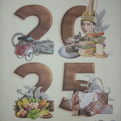 The image is a collage on a light, textured background, featuring four large, brown, stylized numbers forming "2025".
The upper-left section displays a red and black traditional Indonesian pedicab (becak), positioned over a grey bicycle wheel. Behind it, a smaller image depicts a bustling port with numerous boats and waterfront structures, indicative of a busy maritime trade hub, consistent with areas like Sunda Kelapa in North Jakarta.
In the upper-right, the face of a young woman is prominently featured, adorned with an elaborate golden traditional headdress with tall, grey feather-like plumes. Below her, to the left, a pottery wheel holds a partially formed clay pot. To the right, stacks of multi-colored artisanal soap bars (green, pink, purple, yellow, beige) are arranged on small, circular wooden log slices.
The lower-left section showcases an assortment of vibrant traditional Indonesian snacks and desserts (kue) arranged on a woven tray, including various colorful rice cakes, pastries, and fruits such as salak and mangosteen. A smaller woven plate contains a slice of yellow cake, with green folded items next to it. Grey floral patterns accent this arrangement.
The lower-right section features a young woman or girl, dressed in batik-patterned clothing, seated on a small wooden stool. She holds a small tool, appearing to paint a white, folded paper umbrella. Beside her are several intricately woven bags and baskets of various sizes and patterns, some with distinct geometric designs. Grey floral motifs are also present here.
While the image is a symbolic collage representing diverse aspects of Indonesian culture and heritage, the inclusion of a traditional pedicab and a bustling port scene strongly suggests elements found in the Special Capital Region of Jakarta, specifically historical areas like Sunda Kelapa in North Jakarta, known for its maritime trade and traditional transportation. However, the image itself does not depict a specific, identifiable street or landmark within the city.
