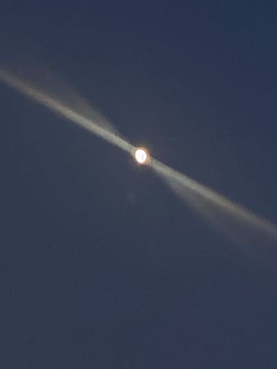 The image shows a night sky in Wysoka, Poland, dominated by a bright light source, likely the moon or a street light, creating a strong light beam effect. The sky is a deep blue, suggesting nighttime. The light source is positioned centrally with the beam appearing to emanate vertically across the frame. There are no people or distinct objects visible beyond the light source.