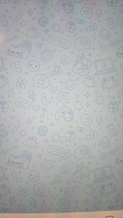 The image shows a light blue textured background covered in a repeating pattern of light blue line drawings of various icons. These icons include smiling faces, a cat, a dog, a unicorn, a frog, a laptop, a camera, a phone, a microphone, a gift box, a heart, a star, a moon, an email symbol, a speech bubble with a ghost, a lightning bolt, a play button, a waveform, a magnifying glass, a checkmark, and a bell. There are no people or recognizable landmarks visible. The image is a digital wallpaper or pattern and does not depict any specific location in Ukhta, Russia.