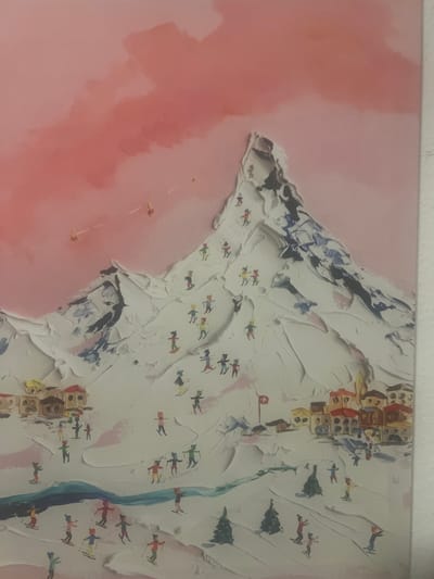 This media file is a close-up, overhead shot of a painting depicting a winter mountain scene with a village. The painting features a textured, impasto style, with thick white paint representing snow-covered slopes. Scattered across the slopes are numerous small figures of skiers in various colorful outfits, engaged in the activity of skiing. Some skiers are shown in dynamic poses, suggesting movement.
Below the snowy slopes, a quaint village is depicted with buildings made of colorful blocks, appearing to be stacked upon one another. A narrow, blue streak suggests a river or a ski run winding through the scene. There are also small, dark green shapes that likely represent pine trees. A small red and white Swiss flag is visible near the village, indicating a potential location in Switzerland.
To the left of the mountain and village, the background is a soft, blurry expanse of pinkish-red, which could represent a sunset or a stylized sky. Several small, bright orange dots are scattered in this pink area, possibly representing distant figures or an abstract element. The overall impression is a vibrant and lively depiction of a ski resort. The time of day is not explicitly indicated but the warm pink tones might suggest either a dawn or dusk setting. The weather appears to be clear and snowy, ideal for skiing.