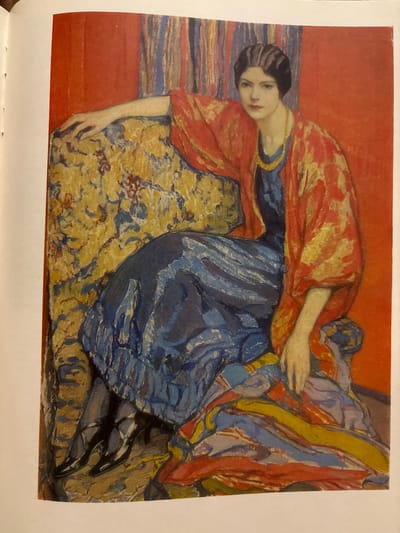 The image is a painting of a woman seated in a chair. The woman has dark hair and is wearing a red and gold patterned shawl over a blue dress. She is looking at the viewer with a neutral expression. The chair she is sitting in is upholstered with a yellow and blue floral pattern. Behind her is a red wall and a striped curtain. The painting is rendered in a bold, impressionistic style with visible brushstrokes. There is no indication of a specific location in Svkh Maslovskiy 1 Otdeleniye, Russia.