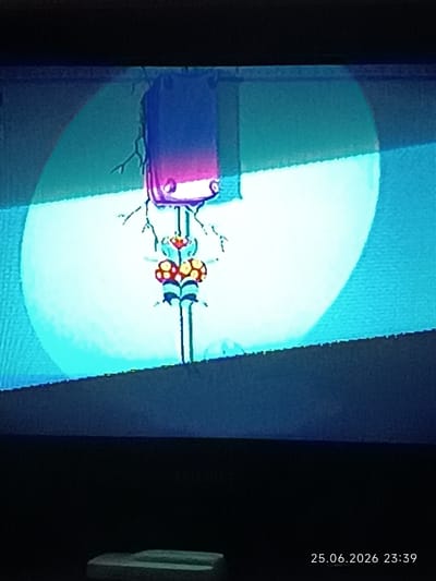 The image shows a cartoonish, vertically oriented character against a bright, illuminated background. The character appears to be metallic or robotic, with a purple rectangular head that has two glowing white eyes. Below the head, a thin neck connects to a central body structure. This body has two prominent red and yellow mushroom-like shapes on either side, with black and blue accents at the bottom. Thin, twig-like lines extend from the head and body, suggesting appendages or electrical connections. The overall scene is abstract and colorful, with a strong blue and light cyan gradient in the background, creating a spotlight effect. A dark, blurry foreground element is visible at the bottom. The image also displays a timestamp in the lower right corner: "25.06.2026 23:39".