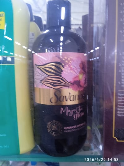 The image shows a close-up of a dark bottle of "Savanna" body wash, with a label featuring a pink and gold floral design and the text "Majestic Glow". The bottle is sitting on a shelf in what appears to be a store, with other bottles visible in the background. To the left, a large yellow bottle is partially visible, and to the right, a dark, rectangular object, possibly another product or a shelf divider, is present. The lighting is bright, suggesting an indoor setting with artificial lights. A timestamp "2026/6/29 14:53" is visible in the bottom right corner, indicating the time the photo was taken. The overall scene appears to be a retail environment, possibly a pharmacy or supermarket, focused on personal care products. There are no people visible in the image.