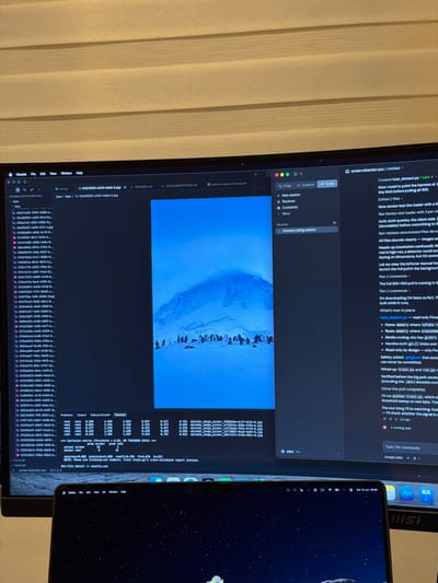The image shows a computer setup with two monitors and a laptop. The primary monitor displays a file explorer on the left, a large image of penguins and icebergs in the center, and a code editor or chat interface on the right. The file explorer shows a list of image files within a "fake" directory. The code editor/chat interface has tabs for "Chat," "Cowork," and "Code," and displays a conversation or log related to a "screen-detection-poc" project, including comments about dataset loading, smoke-testing, and training. The laptop in the foreground displays a starry night wallpaper and the macOS menu bar, indicating the current time is 23:06 on Saturday, June 13th. The background of the scene appears to be a wall with horizontal blinds. There is no indication of the city of Kafr Yasif, Israel, in the image.