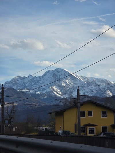 View of snow-capped mountains and a yellow building in Sankt Jakob am Thurn, Austria, through power lines.