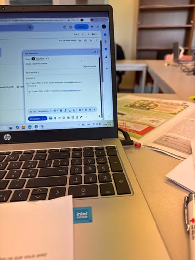 The image shows a laptop with an open email client displaying a reply to an email titled "Re: Exercice 3". The laptop is on a desk, with a keyboard visible. Other items on the desk include papers and a pen. The background shows a blurred view of a room with bookshelves. The scene appears to be an office or study environment. The email client shows sender information, a subject line, and the body of the email. The timestamp on the email indicates it was sent on June 17, 2026, at 14:57. The laptop displays the current time as 15:34 and the date as 17.06.2026. The presence of the "intel inside" sticker suggests the laptop is a Dell or HP brand with an Intel processor. The keyboard has a mix of English and accented characters, indicating a potential European keyboard layout. The environment suggests a typical workspace.