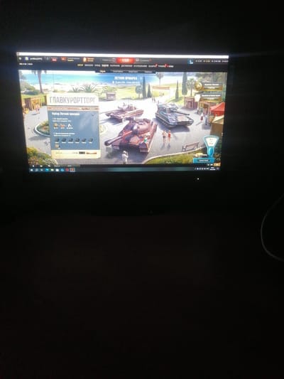 The image is a screenshot of a computer game, likely a tank combat simulator, displayed on a monitor in a dimly lit room. The game interface shows a beach resort backdrop with several tanks in the foreground. Text in Russian is visible on the screen, including "ГЛАВКУРОРТТОРГ" which translates to "Main Resort Fair," and "ЛЕТНЯЯ ЯРМАРКА" meaning "Summer Fair." The game appears to be offering a loot box or a similar purchase mechanism labeled "Набор Летней ярмарки" (Summer Fair Set) with options for purchase. The lower part of the screen shows the Windows taskbar with several application icons and the time "00:10" and date "29.08.2018." The location of Yelsk, Belarus is not depicted or implied in the image.
