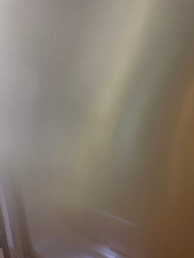 The image depicts a close-up, out-of-focus view of a light-colored, reflective surface. The lighting creates gradients of color, shifting from a pale gray on the left to a warm tan on the right. There are indistinct streaks of light and shadow across the surface, suggesting a glossy or metallic texture. The bottom portion of the image shows a hint of a lighter area, possibly a baseboard or a distinct edge of the surface. The overall impression is abstract and lacks specific identifiable objects or features. The location in Ivanovići, Montenegro, cannot be determined from the visual information provided.