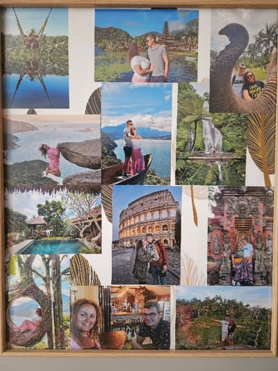 This image displays a rectangular wooden-framed collage containing 13 printed photographs, predominantly featuring an adult male and female couple on vacation. The light brown frame encloses an arrangement of overlapping travel-themed pictures set against a white background with subtle golden feather-like decorative patterns.
Specific scenes depicted across the photographs include:
* A woman on a jungle swing suspended over water, reflecting the sky and foliage.
* The couple standing intimately by a lake with a traditional temple structure and mountains in the background.
* A woman smiling as an elephant's trunk curls around her head.
* A woman in a pink dress appearing to jump or pose on a large rock overlooking a expansive coastline with numerous islands.
* The couple standing on a small boat or platform on a lake surrounded by lush, green mountains.
* The couple on a wooden bridge positioned in front of a multi-tiered waterfall within a dense forest.
* A resort area featuring a swimming pool, thatched-roof buildings, and tropical vegetation.
* The couple kissing in front of the illuminated Colosseum in Rome, Italy.
* The couple posing in front of an ancient, ornate stone temple structure.
* A woman seated in a large, elevated bird's nest-like structure overlooking a body of water and distant hills.
* Individual portrait shots of both the woman and the man.
* The couple standing on a viewpoint overlooking terraced landscapes, likely rice fields.
The people consistently appearing are an adult male and an adult female, suggesting they are a couple. Their actions include posing for photographs, embracing, kissing, and engaging with tourist attractions. The environments are varied and consistent with international tourist destinations, encompassing natural landscapes, iconic historical sites, and resort settings. No identifiable features within the content of the photographs suggest a location within the Cherwell District, United Kingdom; the depicted scenes are exclusively international.