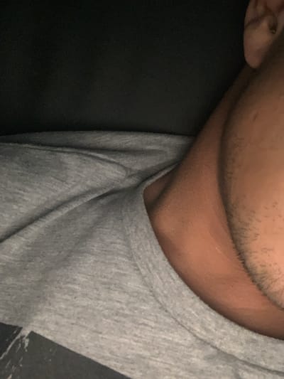 The image shows a close-up view of a person's neck, lower face, and shoulder, wearing a heather gray t-shirt. Part of the left side of the image is black, possibly clothing or a dark background. The person has short facial hair. No information is provided in the image or crops suggesting it was taken in Kalitinovo, Bulgaria.