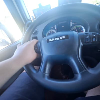 A person is driving a DAF truck. The speedometer reads 83.0. The hand on the tachometer is near the number 10. The image was likely taken in daylight. The location in the city of Pont de Molins, Spain is inferred.