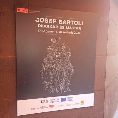 The image shows a poster advertising an exhibition of Josep Bartoli's work, titled "Drawing is Fighting," running from January 17 to May 31, 2026. The poster has a black background with the exhibition details in white text, and features a line drawing of a group of armed individuals. The bottom right of the poster includes logos of supporting organizations, including the Generalitat de Catalunya, Memorial Democràtic, Interreg POCTEFA, and others. The poster is placed on an outdoor surface, likely a paving or stone area. The location is indicated by the logo of MUME, the Museu Memorial de l'Exili (Exile Memorial Museum), located in La Jonquera, Spain.