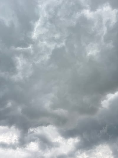 A sky filled with overcast, dark gray clouds, with some patches of lighter gray and white. The clouds are varied in texture and density, creating a sense of depth and movement. There is no visible sky other than clouds. The scene is a close-up, full-frame shot of the sky.