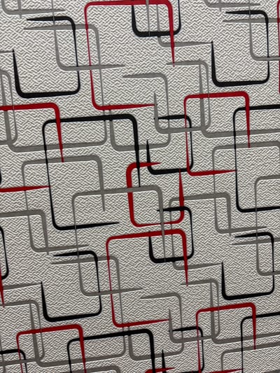 The image shows a close-up, overhead view of a textured wallpaper with a repeating geometric pattern. The pattern consists of interconnected, rounded rectangular shapes in black, red, and gray outlines. The background of the wallpaper has a fine, cross-hatched texture. There are no people, animals, or any discernible environmental features that would indicate a specific location within Novocherkassk, Russia, or any other city. The image solely depicts the wallpaper's surface.