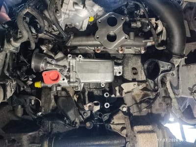 A close-up, overhead view of a vehicle engine bay in Weitnau, Germany. The engine appears to be a diesel engine, with parts such as the exhaust manifold, EGR valve, and various hoses and wiring harnesses visible. The engine is dirty and appears to have some oil residue. The lighting suggests an indoor environment, possibly a garage or workshop. No people are visible in the image. The timestamp "17.07.2026 09:42" is superimposed on the bottom right corner.